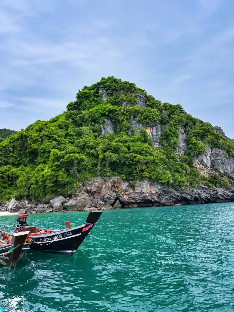 Longtail boats beside a green island in Ang Thong Marine Park