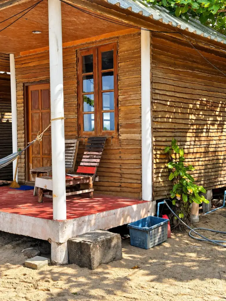 A wooden bungalow with a veranda on the beach at Bottle Beach