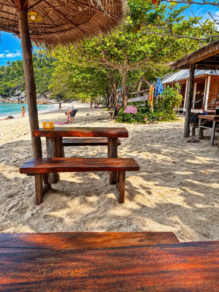 A wooden table in the shade of the trees at Bottle Beach