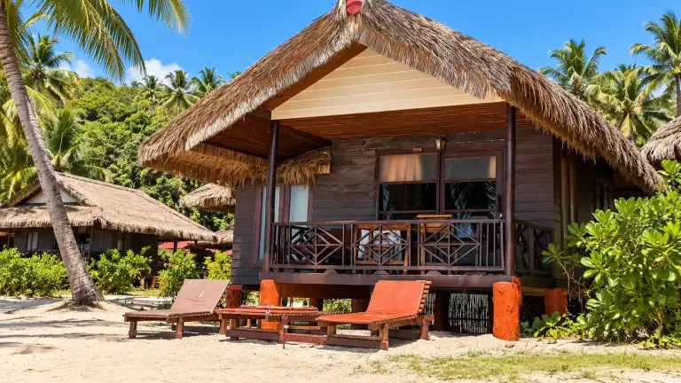 Thatched bungalow and sunloungers on the sand at Bow Thong Beach Resort, north Sairee, Koh Tao