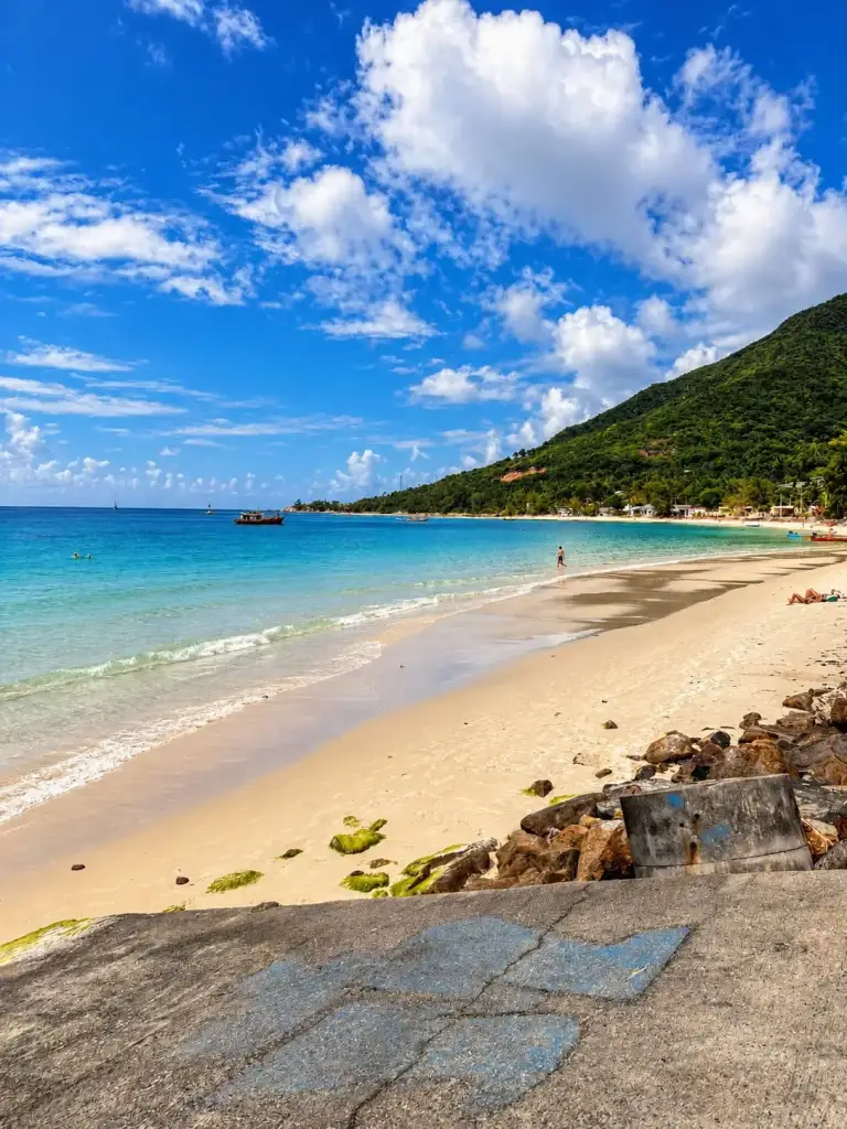 The beach by the pier in Chaloklum, clear water and rocks