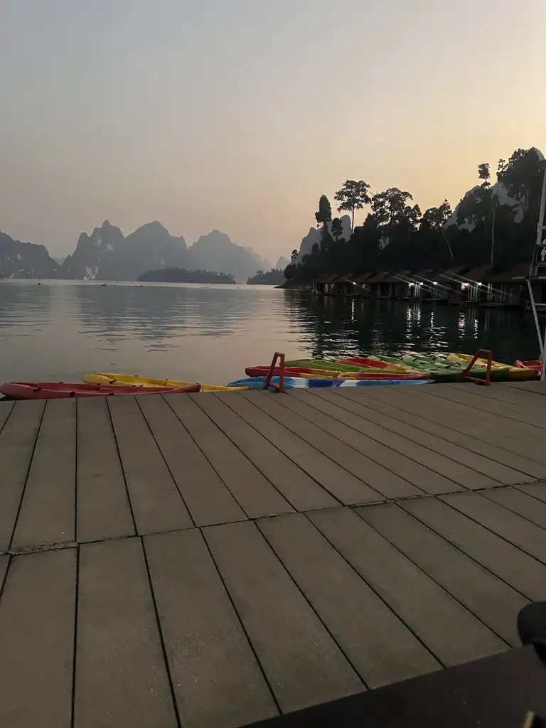 Wooden jetty and kayaks at dusk on Cheow Lan Lake