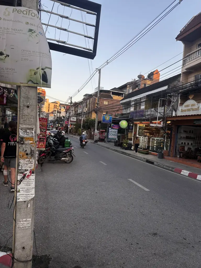 A street in Chiang Mai Old City with shops, scooters and power lines