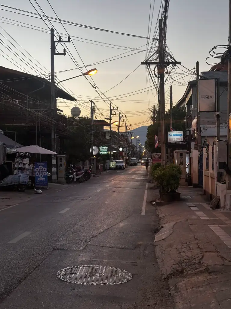 A side street in Chiang Mai in the evening with power lines and street lights