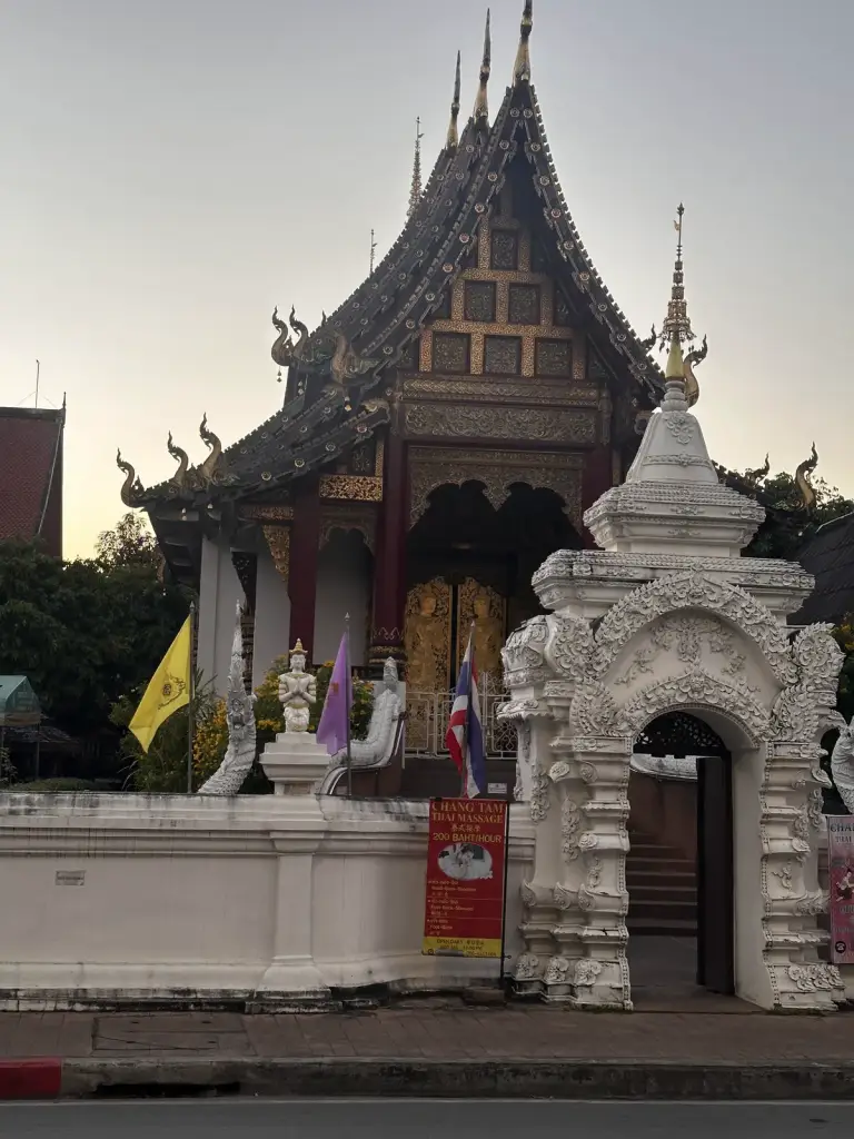 A temple with an ornate northern-style roof and a white gate in Chiang Mai