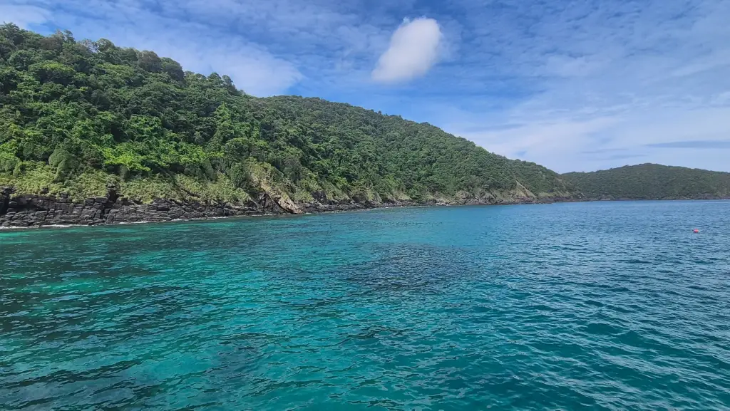 Turquoise water off the rocky green coast of Coral Island