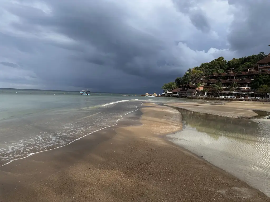 Haad Yao beach on a cloudy morning, with Haad Yao Bayview on the hill at the end of the beach