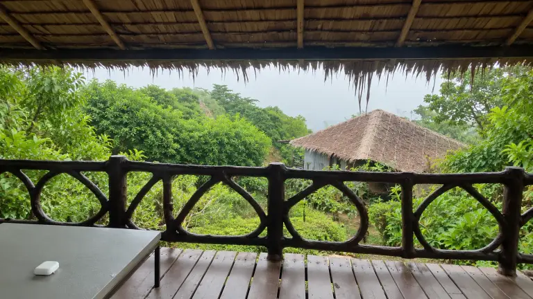Room balcony at HIP Seaview Resort: wooden railing, thatched roof and a hut among the greenery, Koh Phi Phi