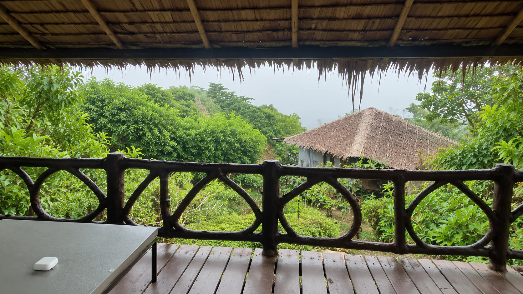 Room balcony at HIP Seaview Resort: wooden railing, thatched roof and a hut among the greenery, Koh Phi Phi
