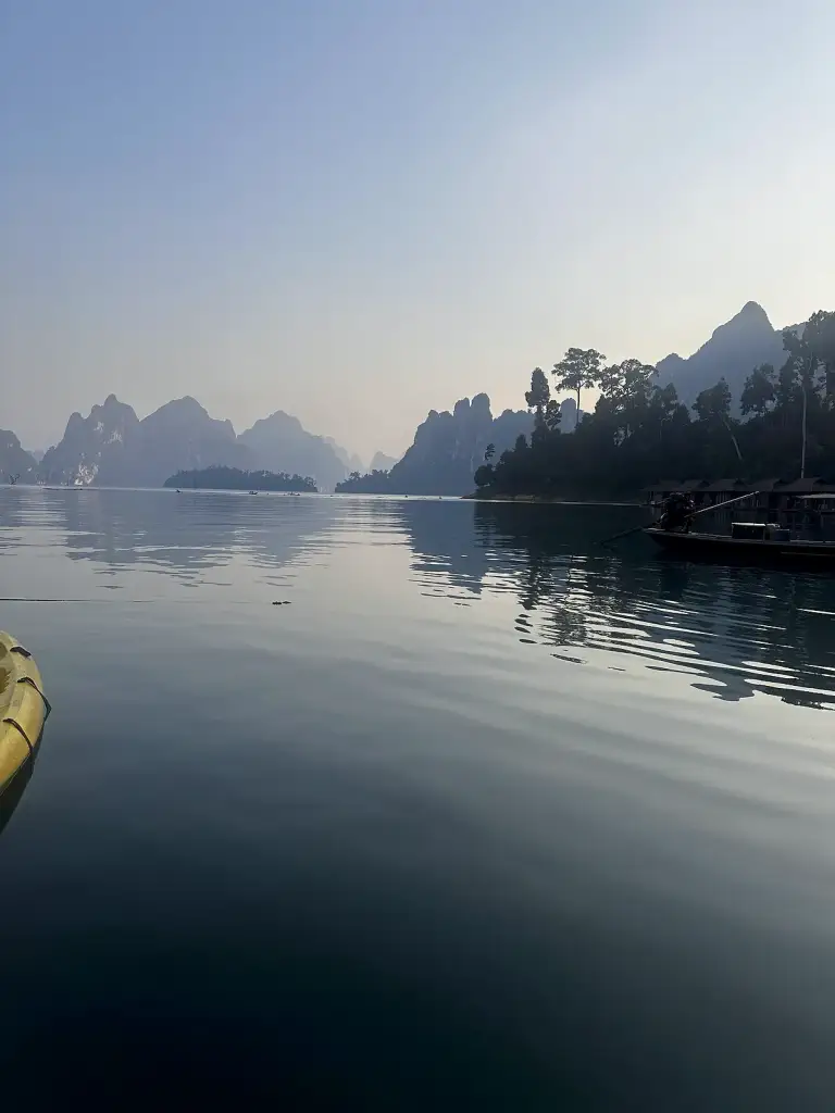 Cheow Lan Lake, calm in the late afternoon, with limestone cliffs and raft houses