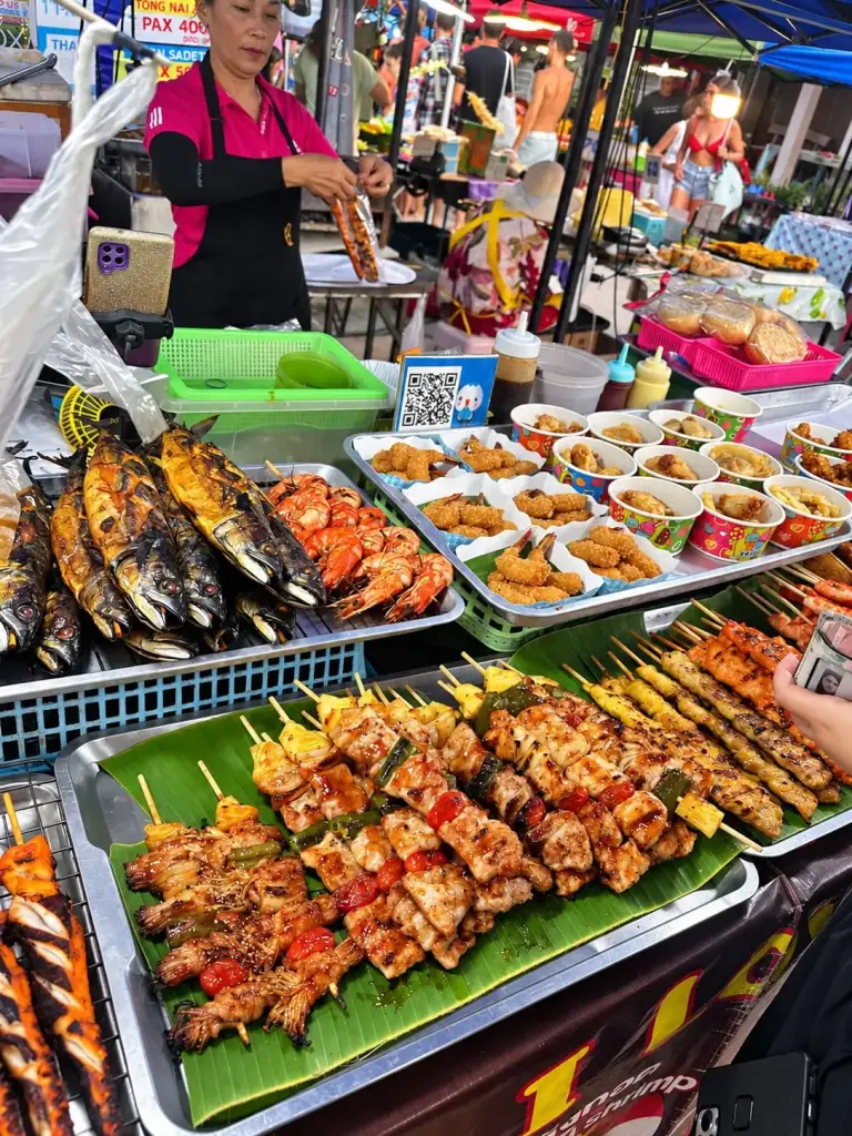 Skewers and fish on the grill at the Chaloklum Sunday market