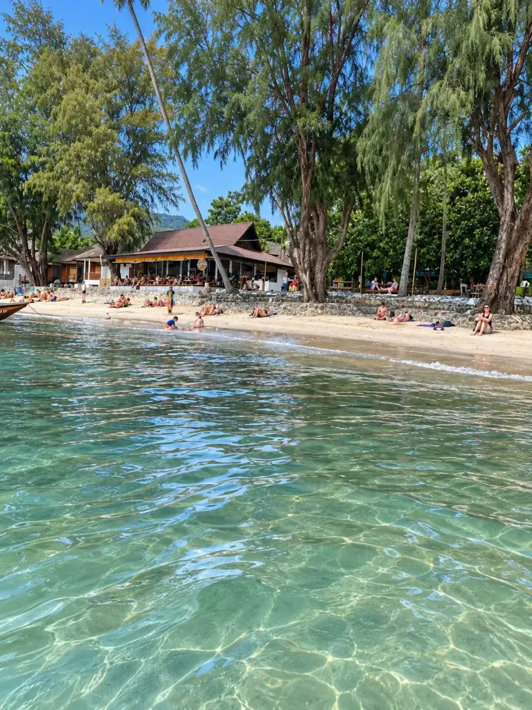 A beach on Koh Tao with trees, a wooden bungalow and clear water