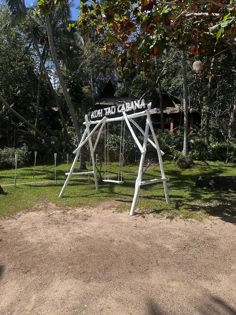Een schommel met een Koh Tao Cabana-bord in de tuin bij het strand