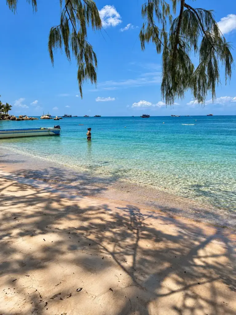The southern end of Sairee Beach, shallow clear water and a small boat, Koh Tao