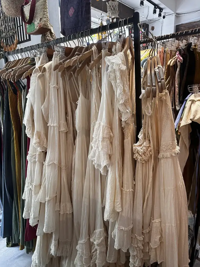 A rail of cream and white ruffled dresses in a shop in Sairee