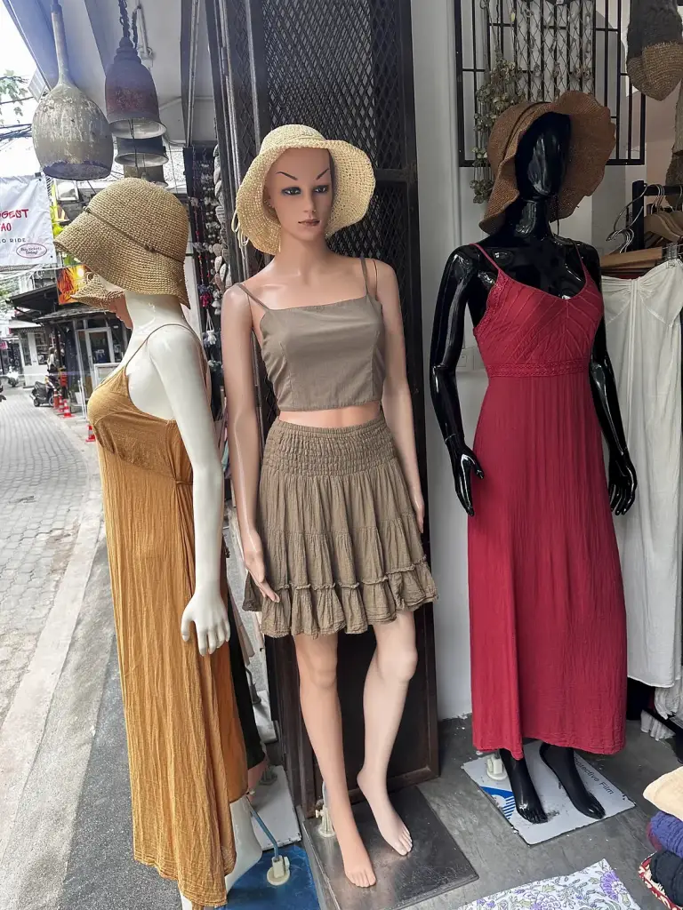 Dresses in sand, khaki and red at a shop entrance in Sairee