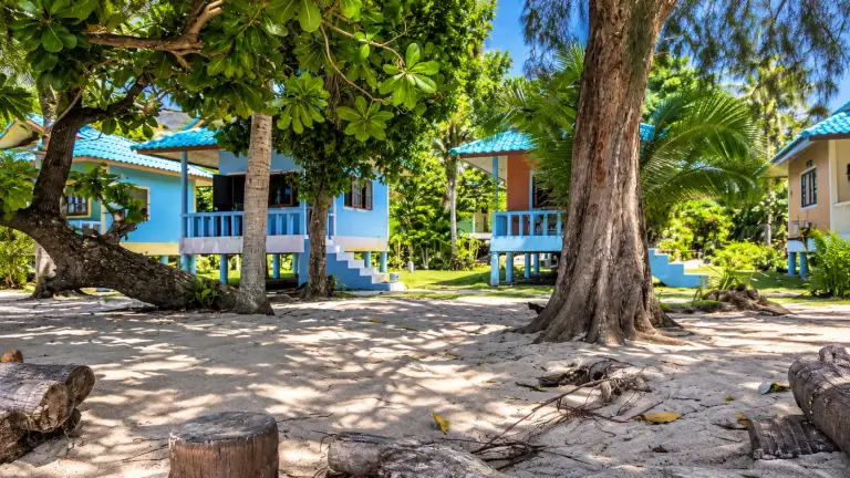 Colourful bungalows on the sand in the shade of trees at Mama O Chai 2 Bungalows, Koh Tao