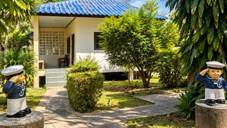 Blue-roofed bungalow and garden path at Nat Resort, with sailor statues at the entrance, Koh Tao
