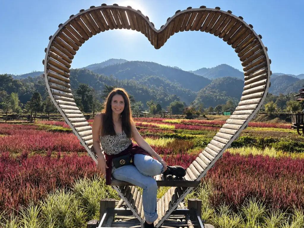 A heart-shaped frame among red flowers and mountains, near the Kho Ku So bamboo bridge