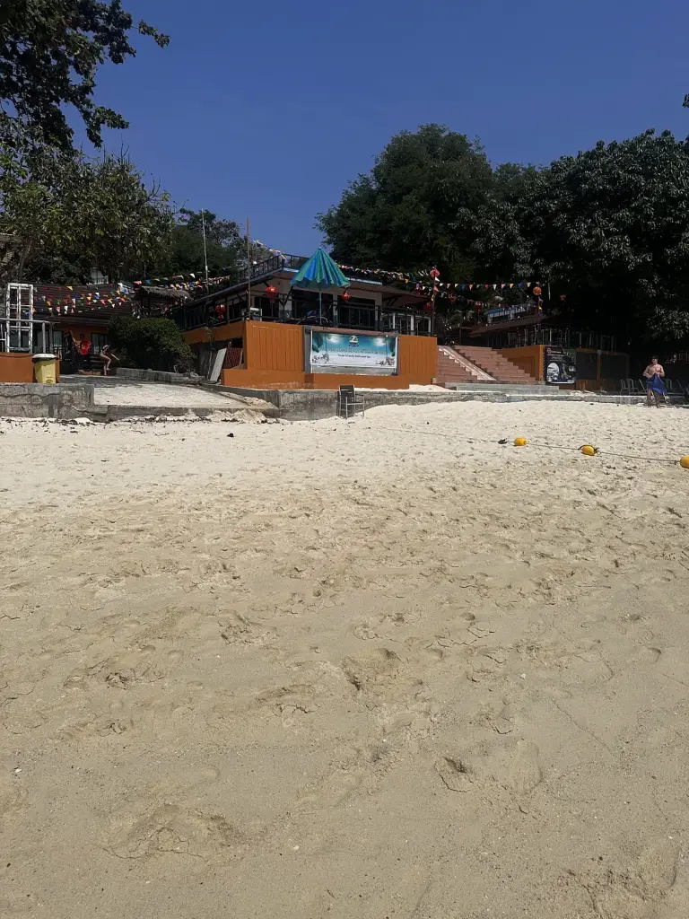 Der weiße Sand des Long Beach auf Koh Phi Phi und ein Hotelgebäude am Strand