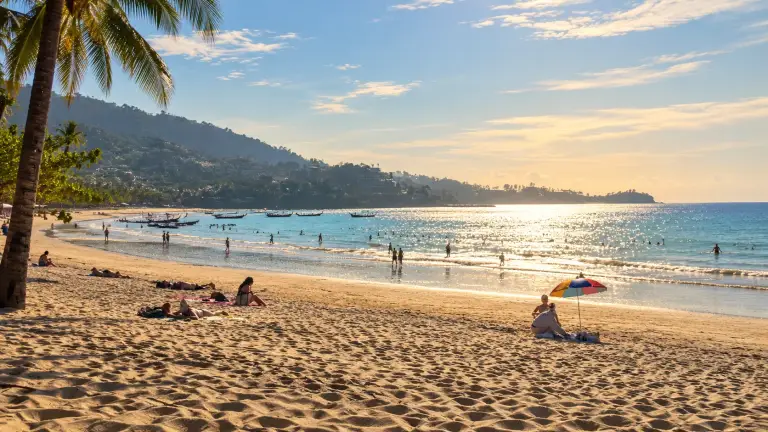 Kamala Beach, Phuket, in the afternoon, with longtail boats and green hills