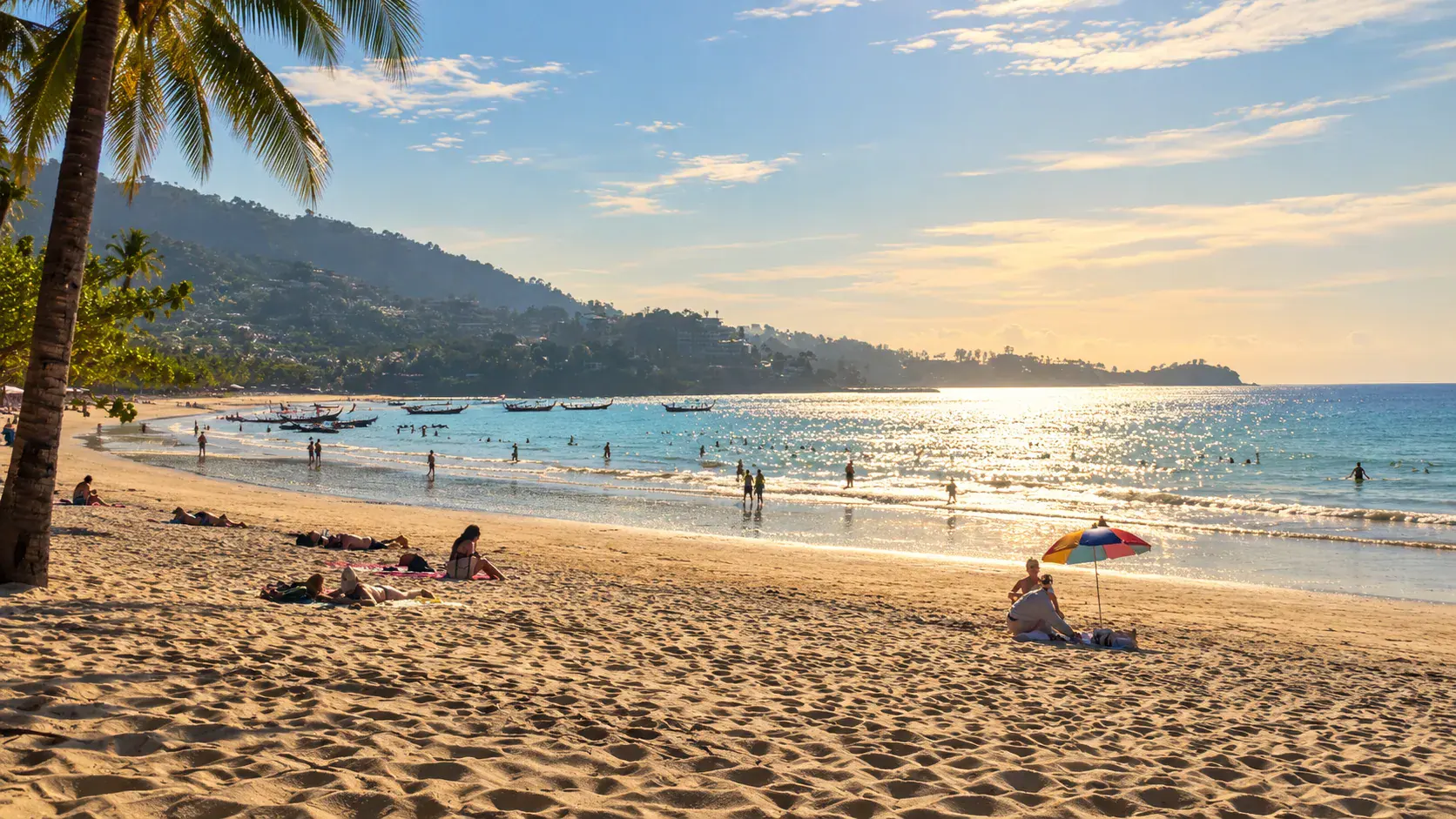 Kamala Beach, Phuket, in the afternoon, with longtail boats and green hills