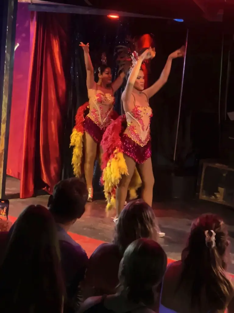 Two dancers in feathers with their arms raised in a dance number, Queen's Cabaret Koh Tao