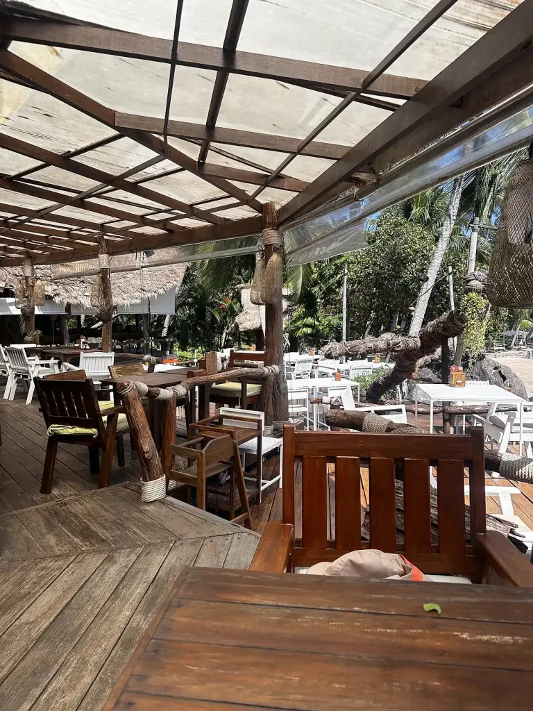Wooden tables in the covered area of Rim Lae