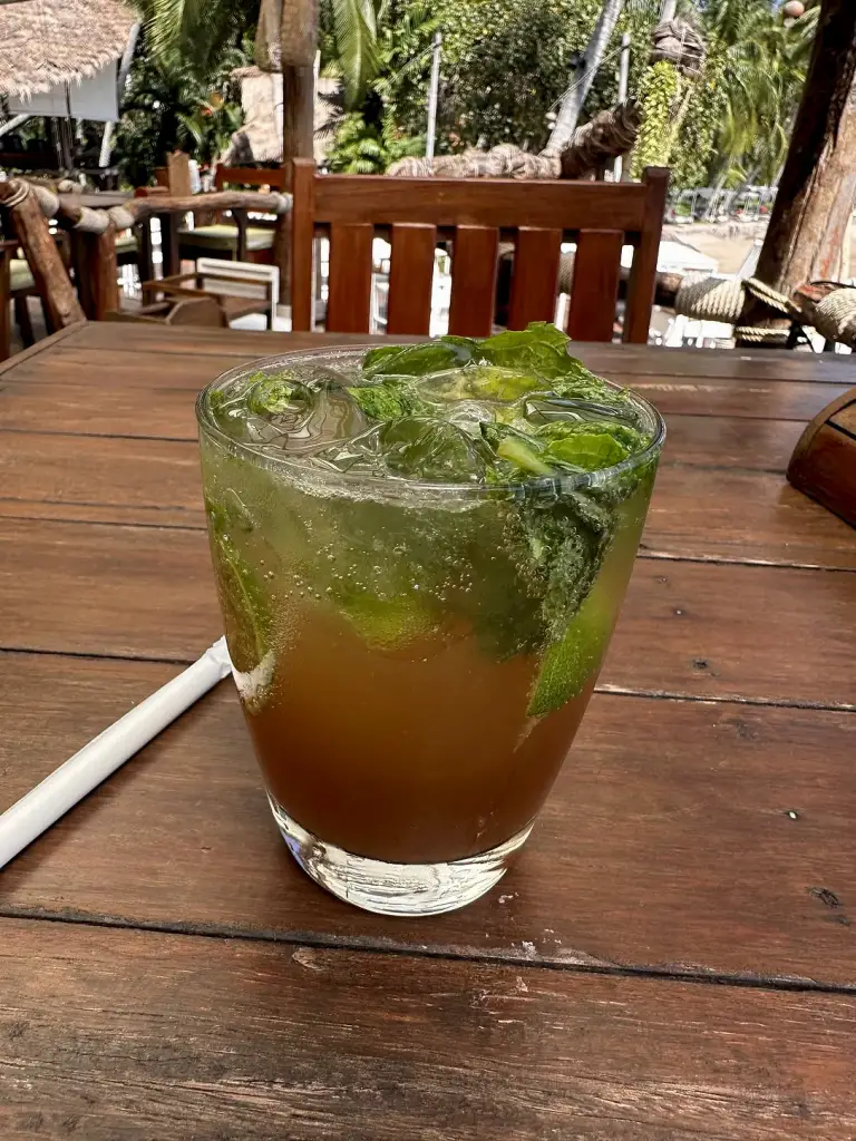 Een cocktail met munt en limoen op een houten tafel bij Rim Lae
