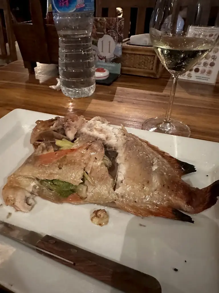 A whole grilled fish and a glass of white wine at Sairee Cottage restaurant
