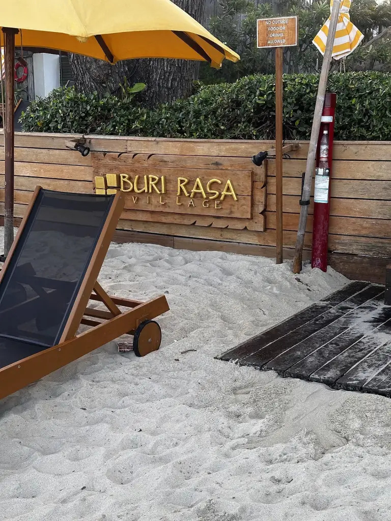 The Buri Rasa Village sign on the sand