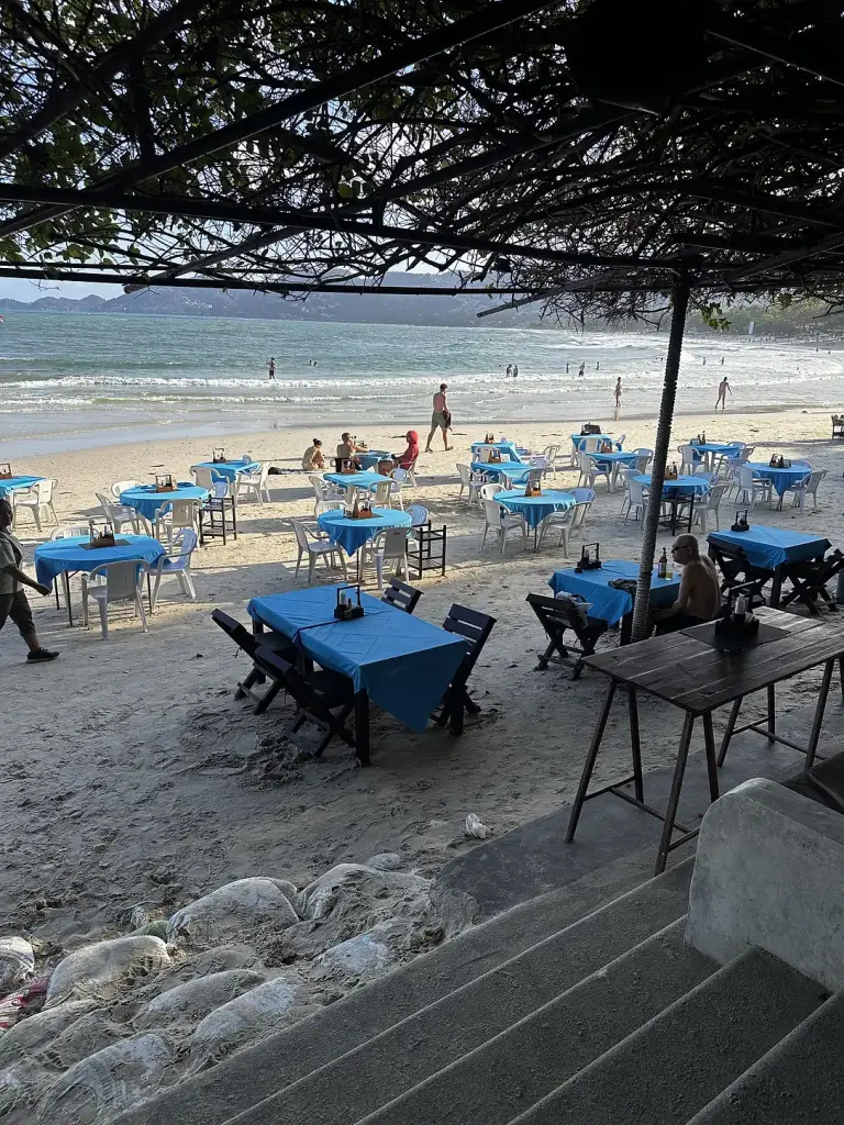 Tables with blue tablecloths on the sand in front of Chaweng Garden