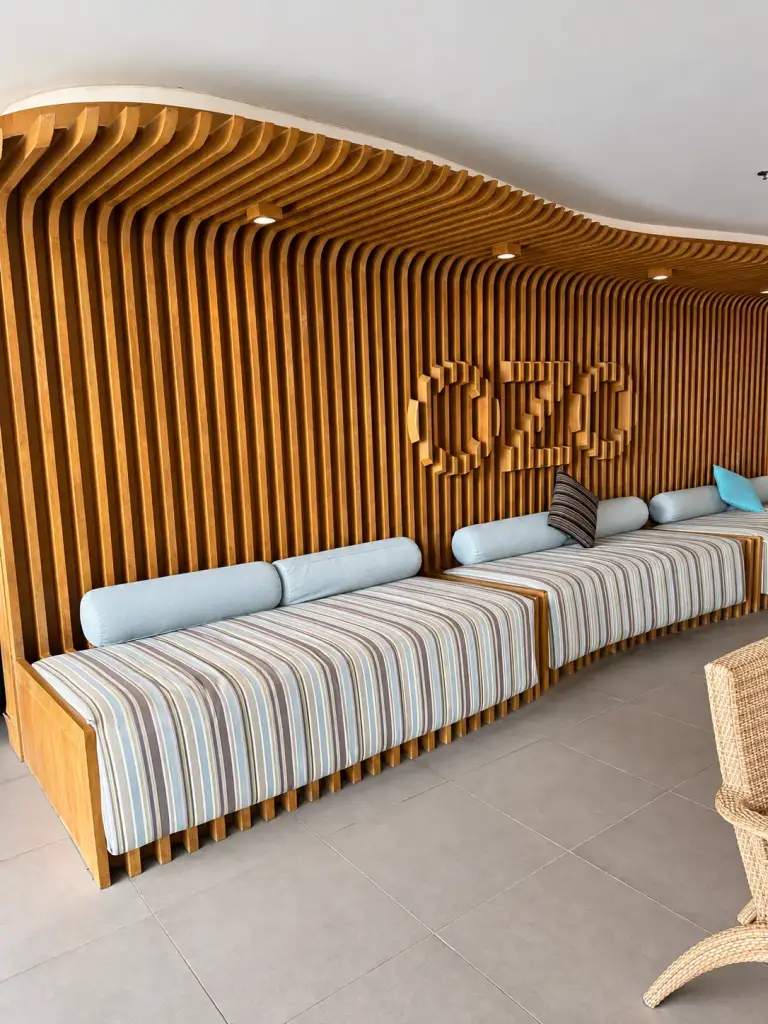 Le lobby de l'OZO Chaweng avec ses canapés rayés et un logo OZO en bois