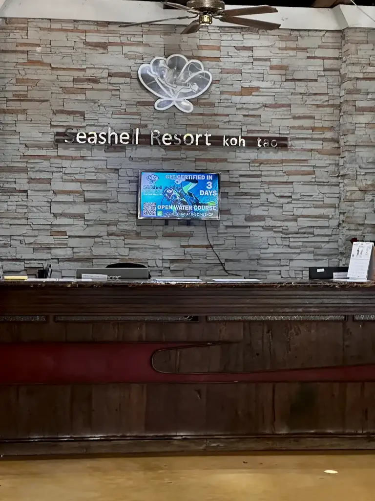 Reception at Seashell Resort Koh Tao, with a stone wall and the hotel sign