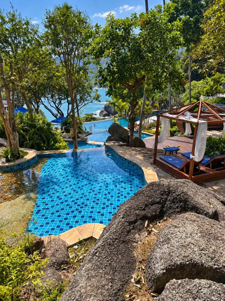 Der Pool, die Felsen und das Balibett im Panviman Resort, mit dem Meer dahinter