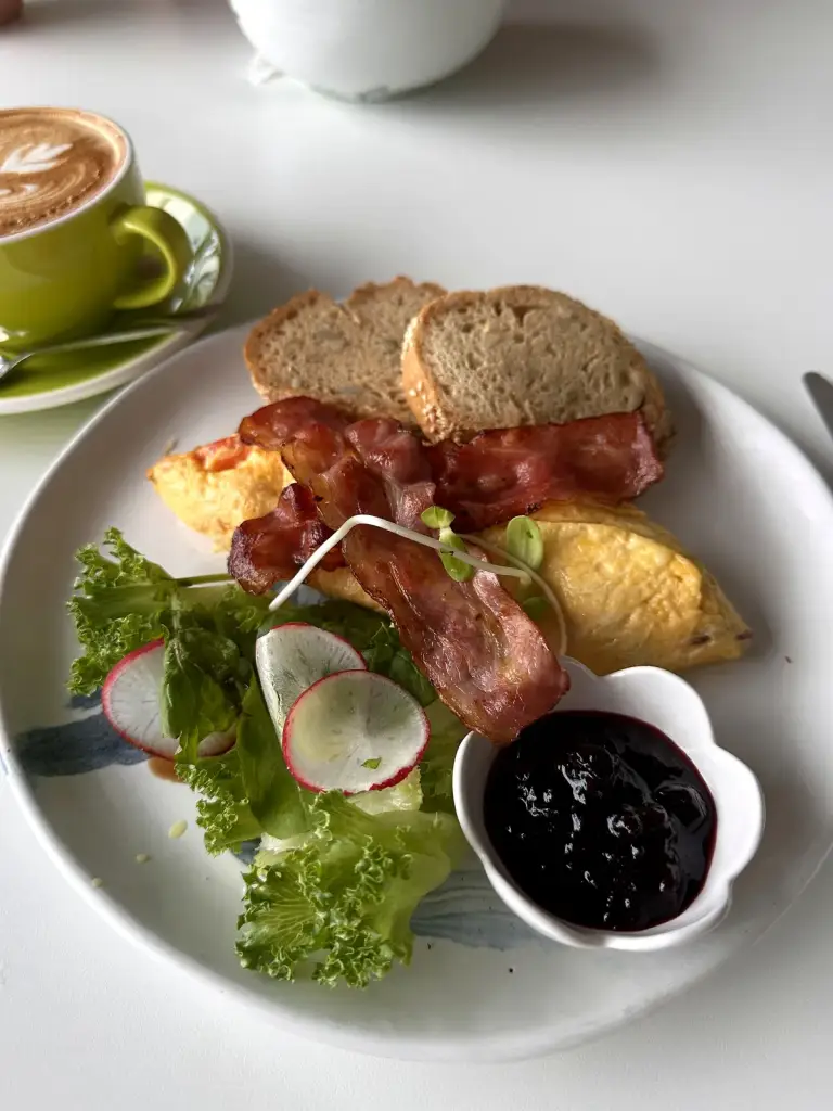 Breakfast at What's Cup: omelette, bacon, gluten-free bread, salad and jam, with a latte