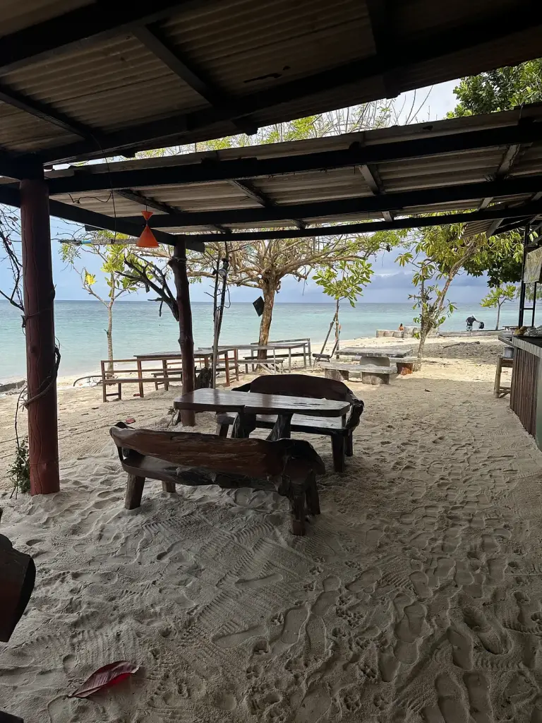 Wooden tables in the shaded seating area on Zen Beach